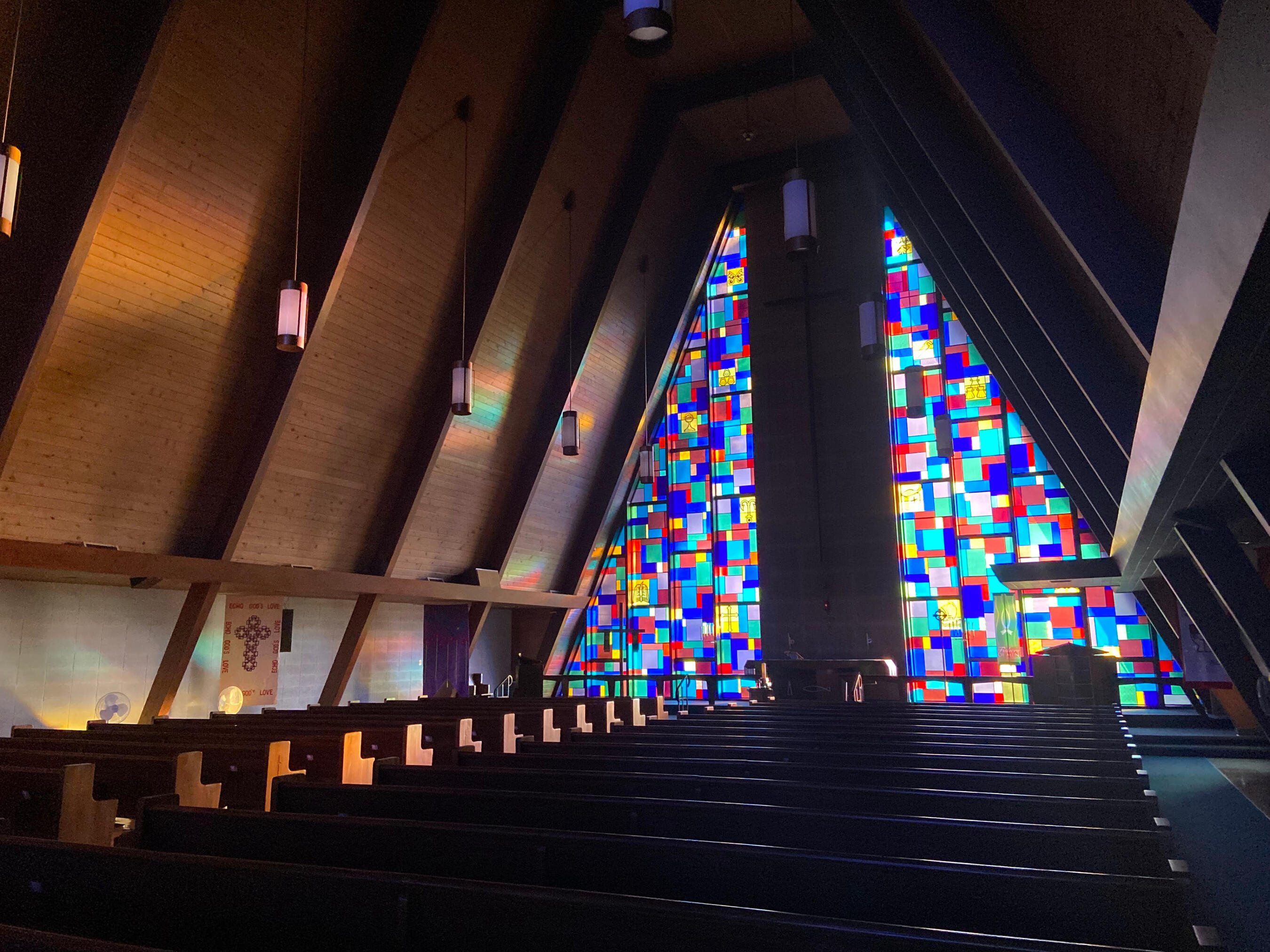 Holy Cross Lutheran Church in Racine, Wisonsin The sanctuary at Holy Cross Lutheran Church in Racine, Wisconsin. It's lit only through the striking stained glass, but with enough light to see the paneled A-frame ceiling and wooden pews.